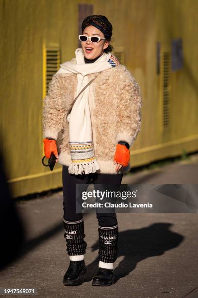 Guest wears beige fur jacket, black pants, beige scarf, Chanel leg warmers, outside Paul Smith, during the Menswear Fall/Winter 2024/2025 as part of...