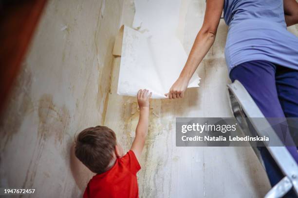 wallpaper removal squad: mom and kid work hand in hand in apartment renovation. - dismantling stock pictures, royalty-free photos & images