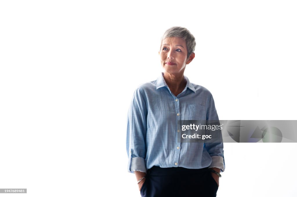 Portrait of senior Asian business woman in business outfit standing against white background