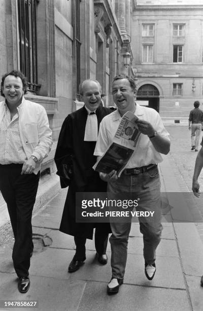 French comic Coluche holds on July 4, 1985 the magazine "L'évènement" with his photo on front page while walking out of the court room with his...