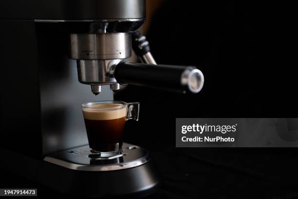Espresso coffee is being poured from an espresso machine into a glass coffee pot.