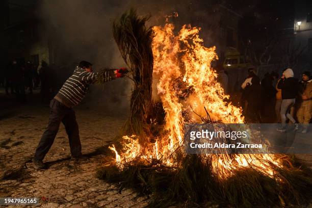Man manage a bonfire during 'Las Luminarias' Festival on January 16, 2024 in San Bartolome de Pinares, Spain. Each year, horses leap through bonfires...