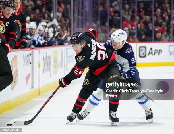 Erik Brannstrom of the Ottawa Senators skates with the puck against Cole Perfetti of the Winnipeg Jets during the second period at Canadian Tire...