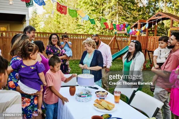 wide shot grandmother laughing with family during birthday party - light vivid children senior young focus foto e immagini stock