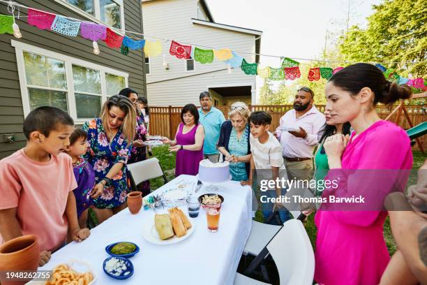 wide shot grandmother cutting cake at backyard family birthday party - light vivid children senior young focus foto e immagini stock