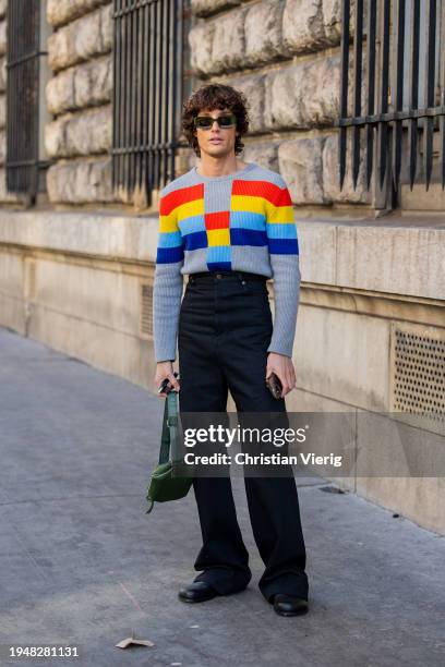 Alex Sánchez de Mora wears Loewe sunglasses, striped grey red yellow blue jumper, high waisted pants, green belt bag outside Loewe during the...