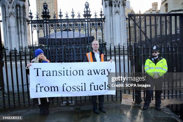 Protesters stand behind a banner reading "Transition Away From Fossil Fuels" during the demonstration. Environmental protesters have congregated...