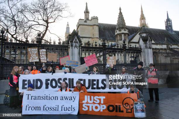 Protesters hold up placards and stand behind anti-fossil fuels banners during the demonstration. Environmental protesters have congregated outside...