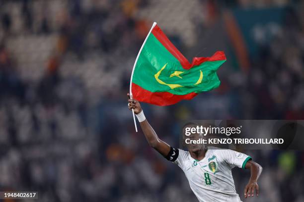 Mauritania's midfielder Bodda Mouhsine holds a Mauritania flag after his team won the Africa Cup of Nations 2024 group D football match between...