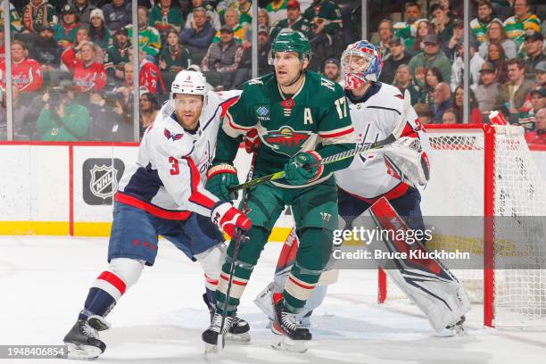 Nick Jensen and Darcy Kuemper of the Washington Capitals defend against Marcus Foligno of the Minnesota Wild during the game at the Xcel Energy...