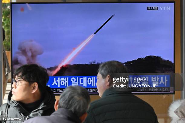 People watch a television screen showing a news broadcast with file footage of a North Korean missile test, at a railway station in Seoul on January...