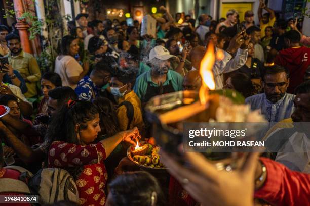 This picture taken on January 23, 2024 shows Hindu devotees preparing their offerings as they gather on the street to pray in front of Lord Muruga's...