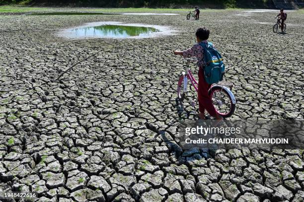 Children play at a dry reservoir for paddy fields due to drought in Kuta Cot Glie, Aceh province on January 24, 2024.