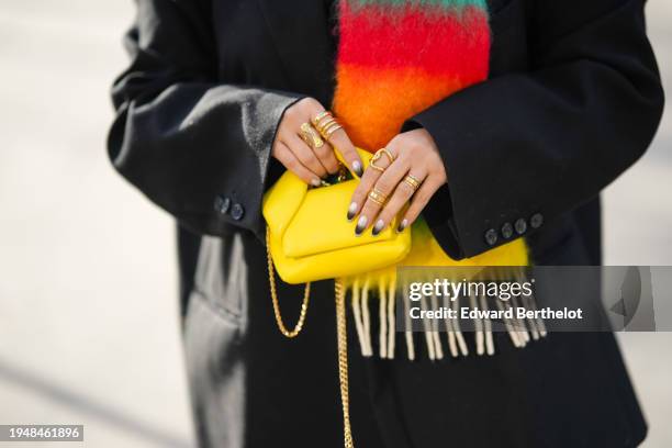 Samia Laaboudi wears a neon orange / yellow / red / green striped print pattern fluffy wool large scarf from Loewe, a black oversize blazer from The...