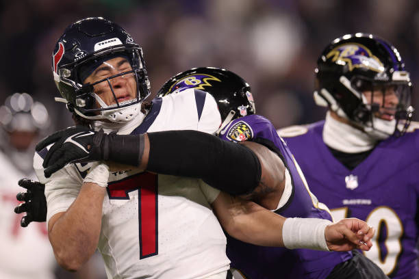 Broderick Washington of the Baltimore Ravens wraps up C.J. Stroud of the Houston Texans during the fourth quarter in the AFC Divisional Playoff game...