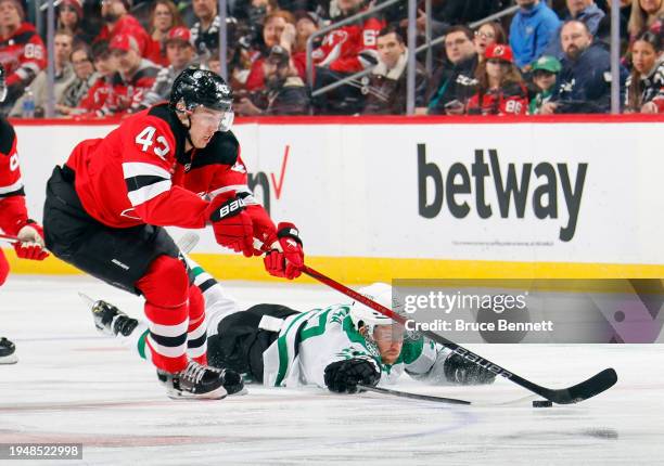 Luke Hughes of the New Jersey Devils and Radek Faksa of the Dallas Stars battle for the puck during the first period at Prudential Center on January...