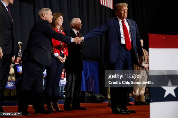 Republican presidential candidate and former President Donald Trump shakes hands with Rep. Joe Wilson as a group of South Carolina politicians join...