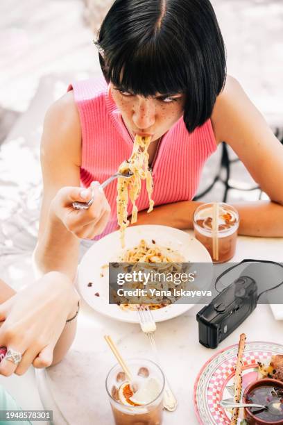 a beautiful young woman eating pasta with pleasure and passion - silver spoon in mouth stock pictures, royalty-free photos & images