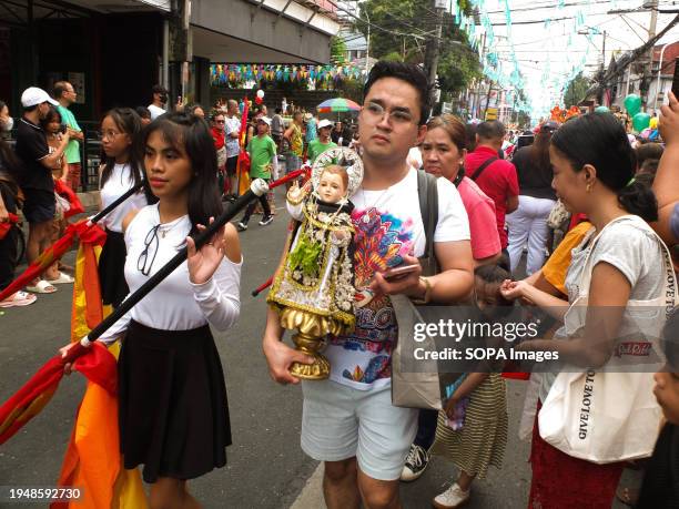 Devotee carries his image of Santo Niño during the parade. The Feast of Santo Niño, honoring the Holy Child Jesus, is observed every third Sunday of...
