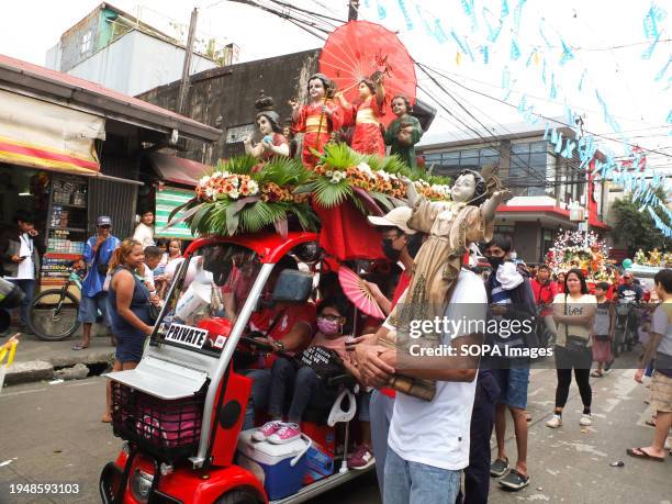 Devotee carries his image of Santo Niño while looking at a Japanese-inspired float with images of Santo Niño wearing kimonos during the parade. The...