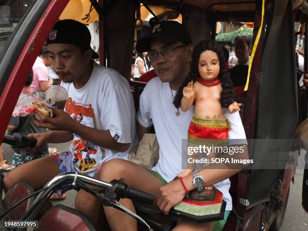 Devotee carries his image of Santo Niño inside his tricycle during the parade. The Feast of Santo Niño, honoring the Holy Child Jesus, is observed...