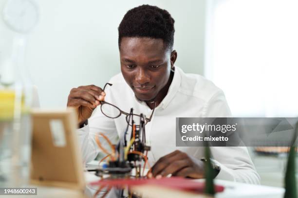 young man making robotic arm at office - creative space stock pictures, royalty-free photos & images