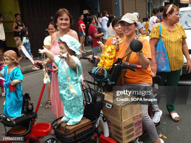Woman carrying her Santo Niño images on her electric bike participates during the parade. The Feast of Santo Niño, honoring the Holy Child Jesus, is...
