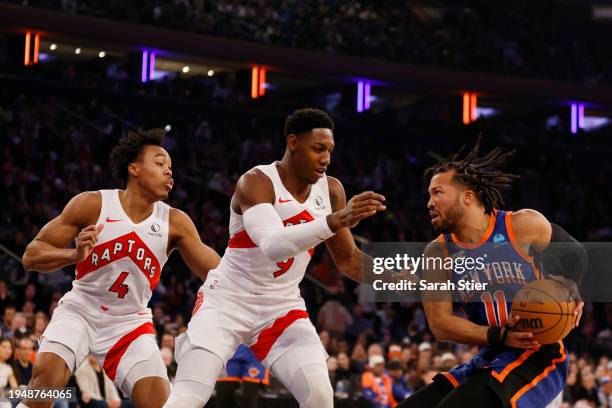 Jalen Brunson of the New York Knicks dribbles against Scottie Barnes and RJ Barrett of the Toronto Raptors during the first half at Madison Square...