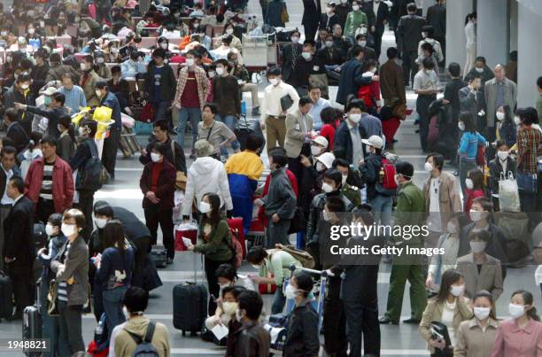Passengers wear masks to protect against the SARS virus as they wait April 24, 2003 at the Beijing Airport in Beijing, China. Thousands have been...