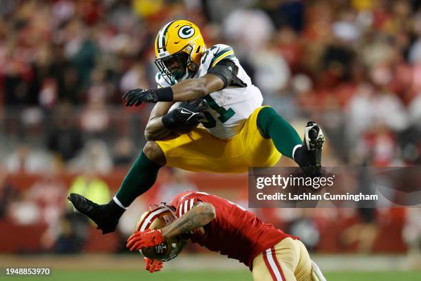 Emanuel Wilson of the Green Bay Packers hurdles Charvarius Ward of the San Francisco 49ers during the fourth quarter in the NFC Divisional Playoffs...