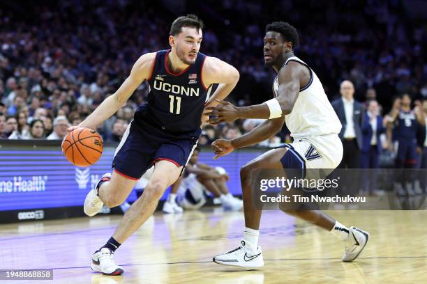 Alex Karaban of the Connecticut Huskies drives past TJ Bamba of the Villanova Wildcats during the first half at the Wells Fargo Center on January 20,...