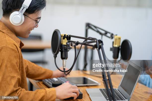 young woman and young man wearing headphones recording a podcast in a studio - radio stock pictures, royalty-free photos & images