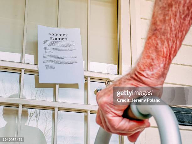 elderly man with a walker facing an eviction notice on the front door of a home - political uncertainty stock pictures, royalty-free photos & images