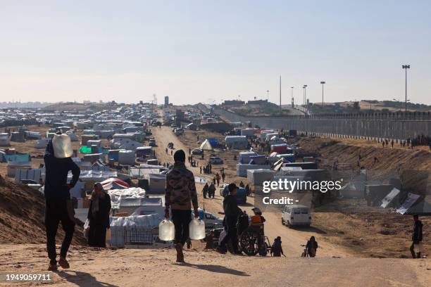People ferry water at a makeshift tent camp for displaced Palestinians in Rafah near the border with Egypt in the southern Gaza Strip, on January 24,...
