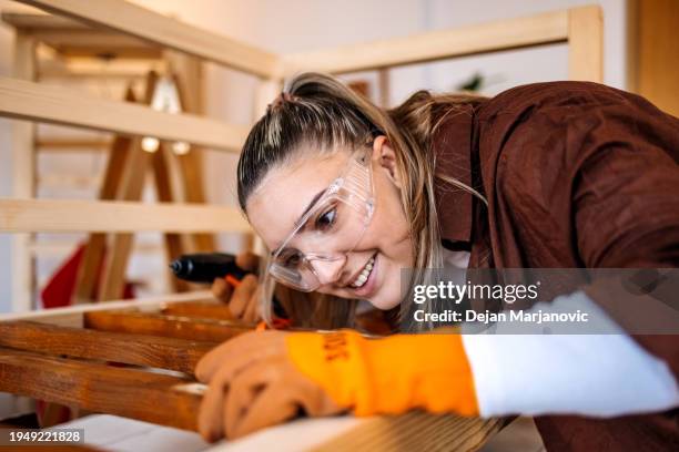 woman starting small business working as carpenter using drilling machine - timber workshop stock pictures, royalty-free photos & images