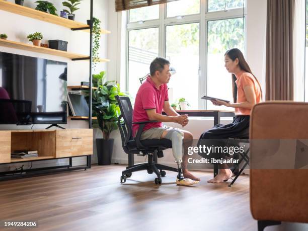 amputee patient with woman at home - ibnjaafar stock pictures, royalty-free photos & images