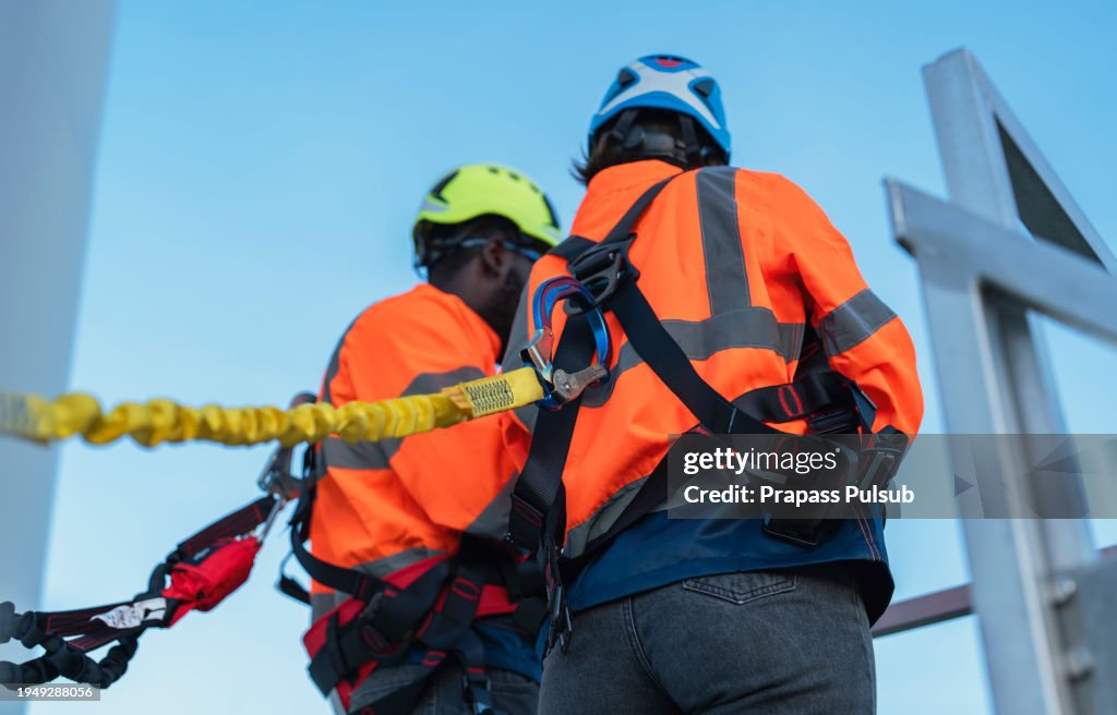 Construction worker wearing safety harness and safety line working at high place - stock photo