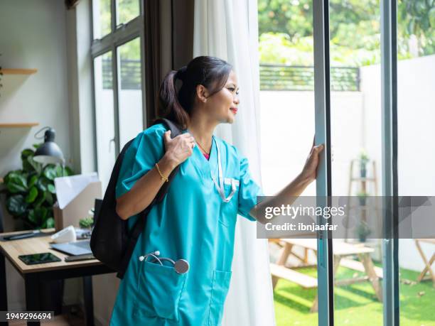 nurse in scrubs looking through the window - ibnjaafar stock pictures, royalty-free photos & images