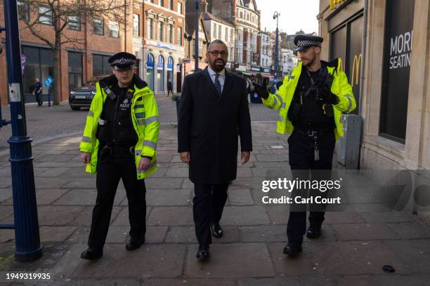 Britain's Home Secretary, James Cleverly, is accompanied by police officers as he walks along Gravesend High Street on January 24, 2024 in Gravesend,...