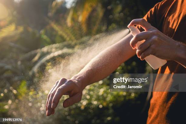 man while applying insect repellent - mückenschutz stock-fotos und bilder
