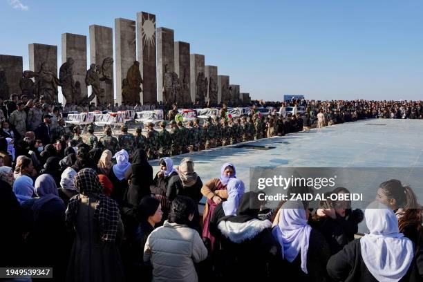 People attend a funeral ceremony for the remains of 41 victims from the Yazidi minority, who were executed by Islamic State group militants in 2014,...