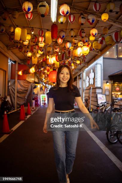 woman walking on japanese izakaya street after work - gold streamer stock pictures, royalty-free photos & images