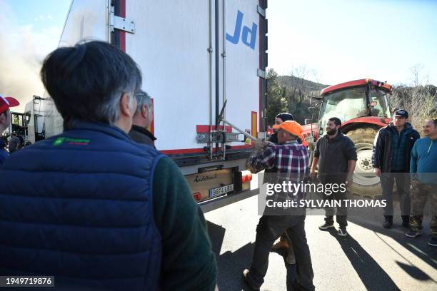 French farmers unload a truck carrying frozen vegetables from Belgium as they block the a roundabout on the Nationale 7 route accessing the...