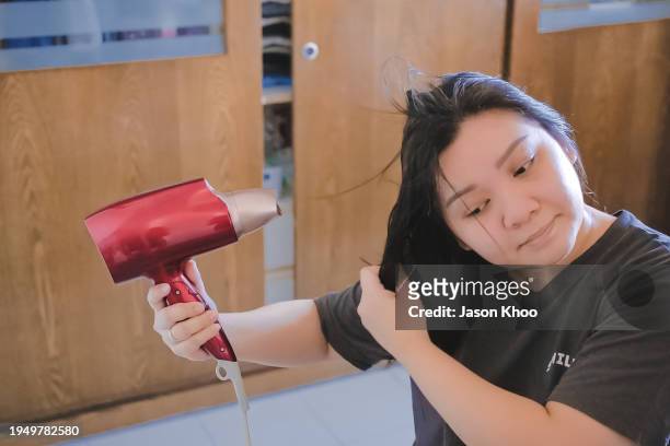 femme asiatique séchant les cheveux avec un sèche-cheveux dans la chambre à coucher - dry hair photos et images de collection
