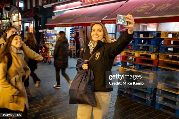 Street scene in Chinatown on as female visitors take a selfie on a smartphone17th January 2024 in London, United Kingdom. Chinatown is an ethnic...