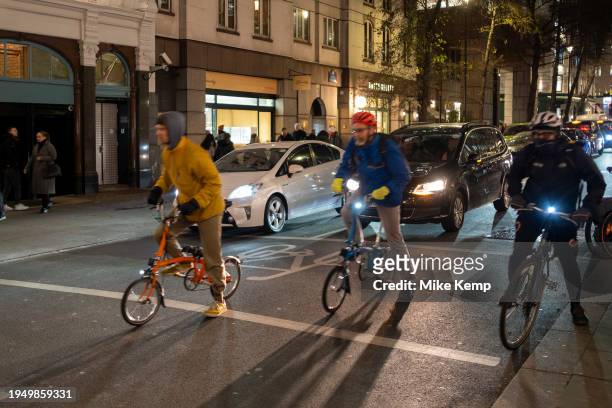 Two cyclists on Brompton folding bikes take off after waiting at traffic lights in the West End on 17th January 2024 in London, United Kingdom....