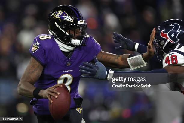 Quarterback Lamar Jackson of the Baltimore Ravens eludes linebacker Christian Harris of the Houston Texans during the second quarter in the AFC...