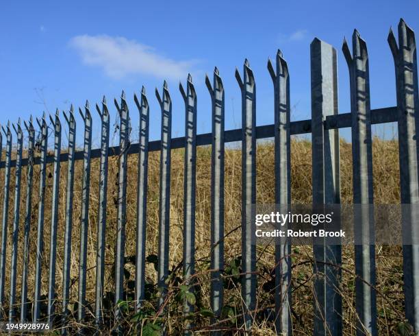 palisade fence with brownfield land beyond - beyond stock pictures, royalty-free photos & images