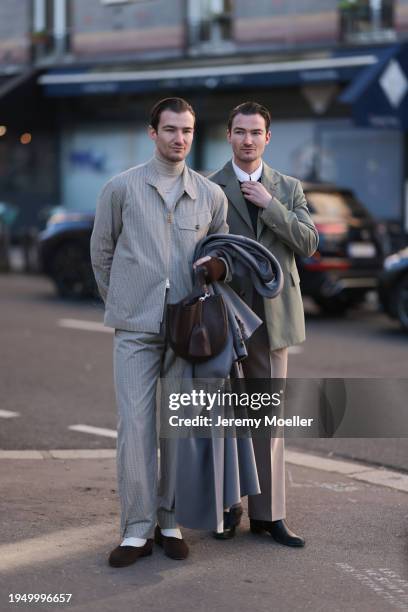 Brett Staniland is seen wearing a grey jacket with beige turtleneck, grey trousers with pinstripes, white socks and brown shoes, and a grey wool coat...