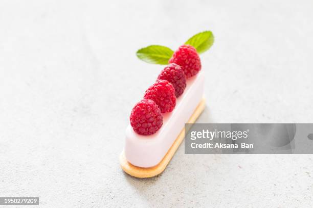 modern dessert. raspberry cream cakes on cookies, decorated with fresh raspberries. light grey background. close up - cream cake stock pictures, royalty-free photos & images
